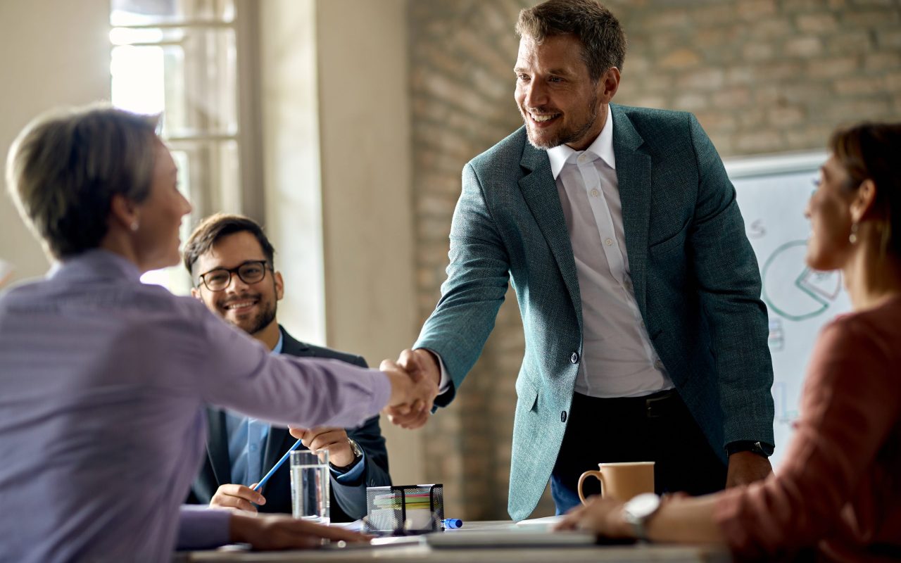Business coworkers shaking hands during a meeting in the office. Focus is on a businessman.